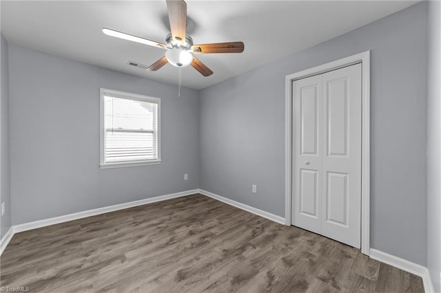 unfurnished bedroom with wood-type flooring, ceiling fan, and a closet