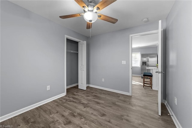 unfurnished bedroom with a closet, ceiling fan, wood-type flooring, and stainless steel fridge