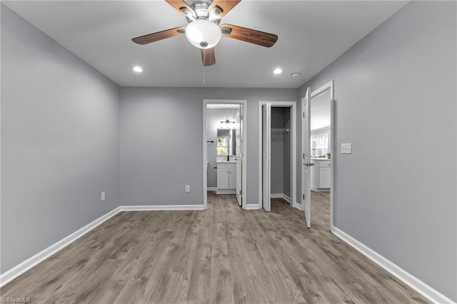 unfurnished bedroom featuring ensuite bath, ceiling fan, and light hardwood / wood-style flooring