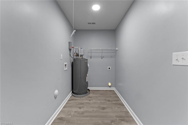 washroom with electric water heater, washer hookup, hookup for an electric dryer, and light hardwood / wood-style flooring