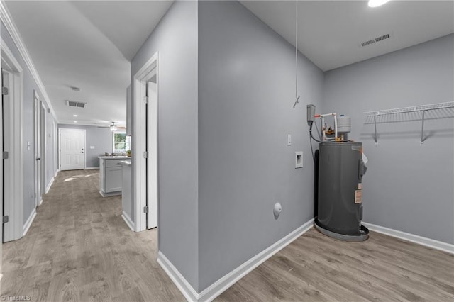 interior space with water heater, hookup for a washing machine, and light hardwood / wood-style flooring