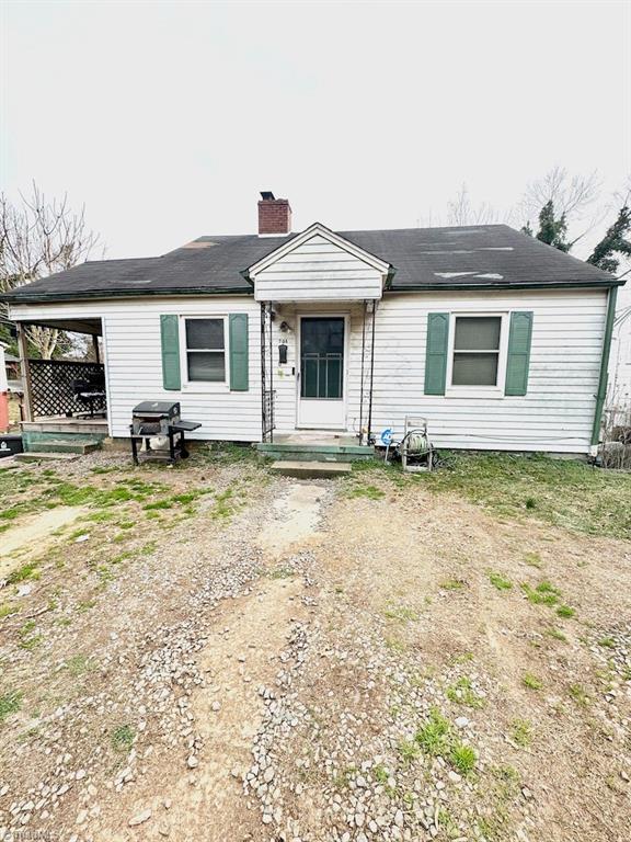 view of front facade with dirt driveway and a chimney