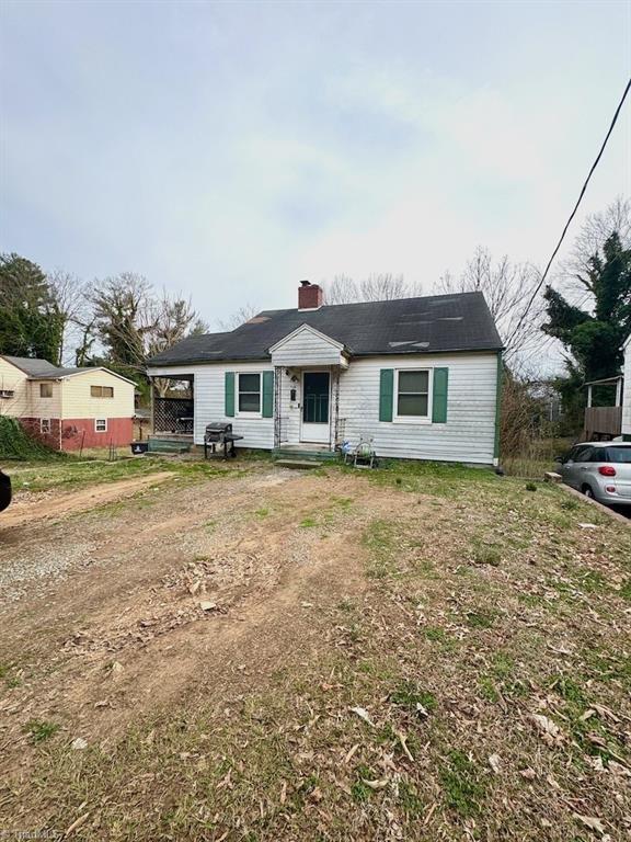 view of front of house featuring entry steps, driveway, and a chimney