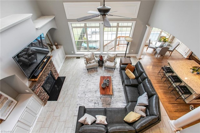 living room with ceiling fan, light hardwood / wood-style flooring, and a fireplace