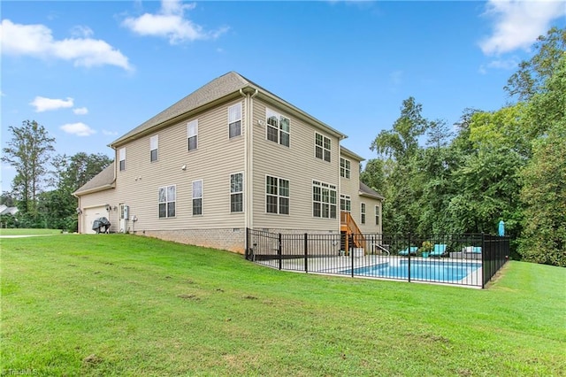 back of property with a fenced in pool and a yard