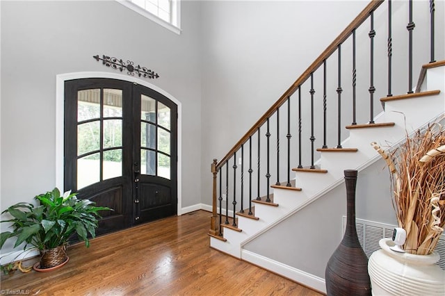 foyer entrance with a high ceiling, wood-type flooring, and french doors