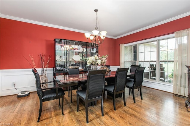 dining space with hardwood / wood-style flooring, crown molding, and a notable chandelier