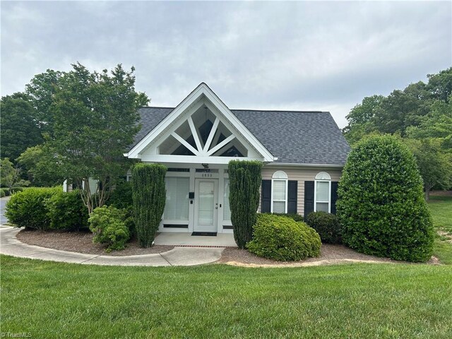 view of front of house with roof with shingles and a front lawn