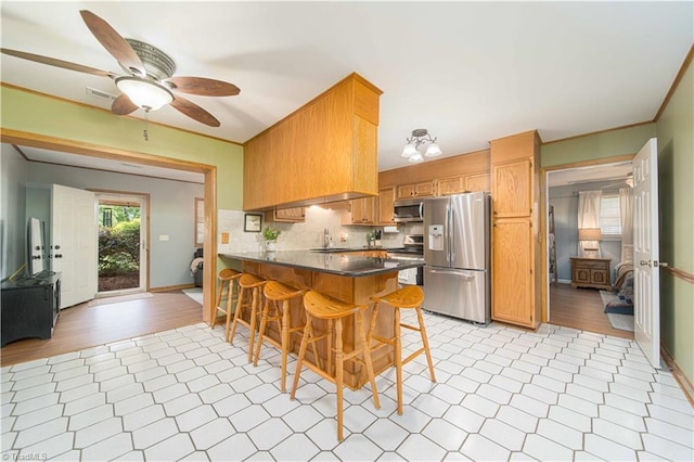 795 Morris Rd, Winston-Salem, NC 27101 - kitchen featuring stainless steel appliances, a peninsula, dark countertops, ceiling fan, and healthy amount of natural light