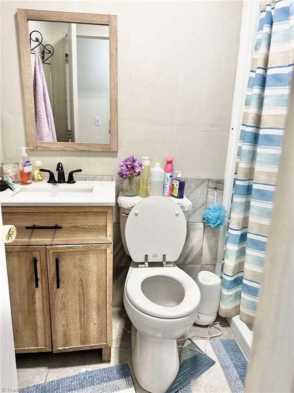 bathroom featuring vanity, curtained shower, tile patterned floors, and toilet