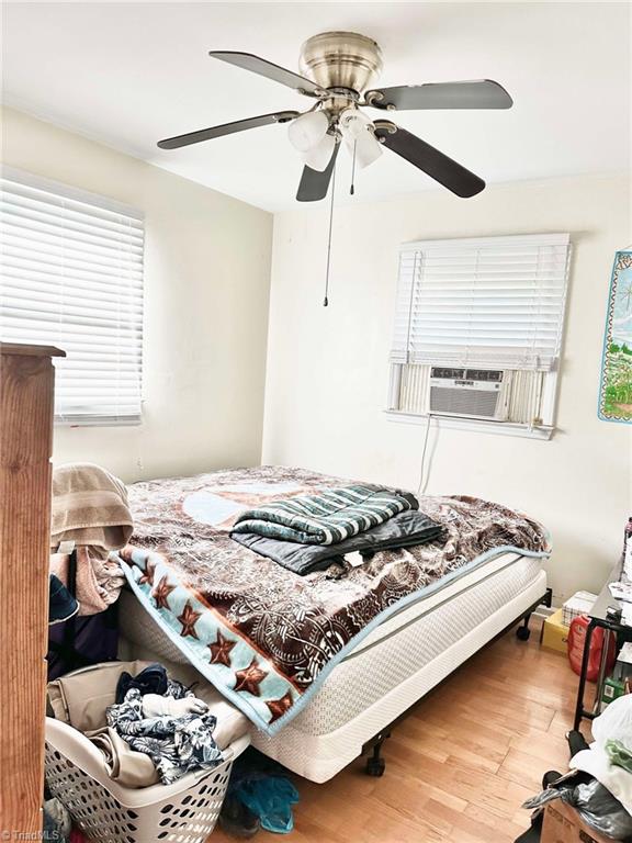 bedroom featuring cooling unit, hardwood / wood-style flooring, and ceiling fan