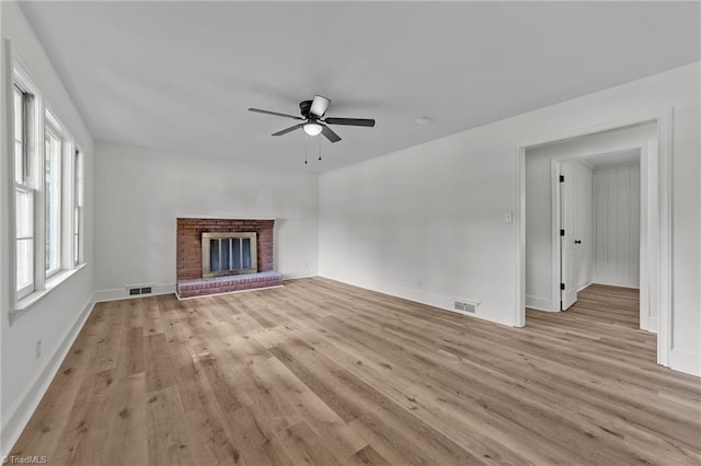 unfurnished living room featuring ceiling fan, light wood-type flooring, a fireplace, and baseboards