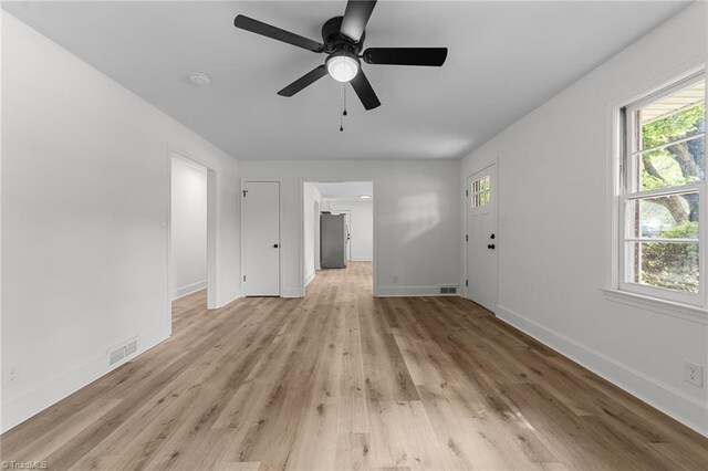 unfurnished living room featuring healthy amount of natural light, baseboards, and light wood finished floors