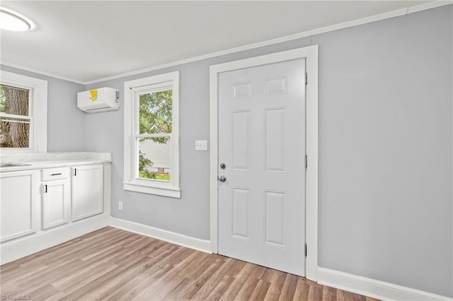 interior space with ornamental molding, sink, light hardwood / wood-style floors, and a wall mounted AC