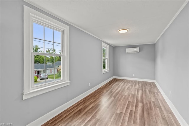 spare room with an AC wall unit, hardwood / wood-style flooring, plenty of natural light, and ornamental molding