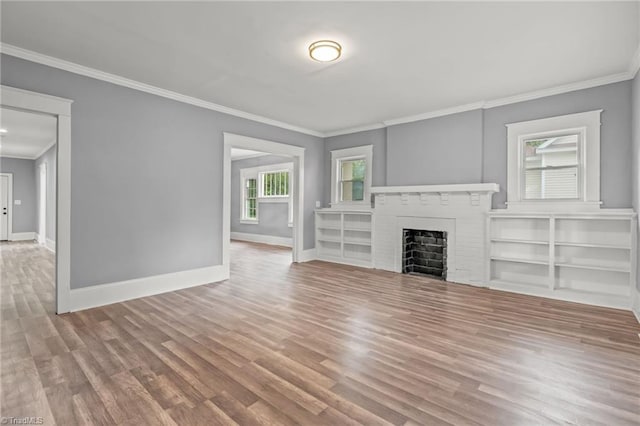 unfurnished living room featuring wood-type flooring, crown molding, and a brick fireplace