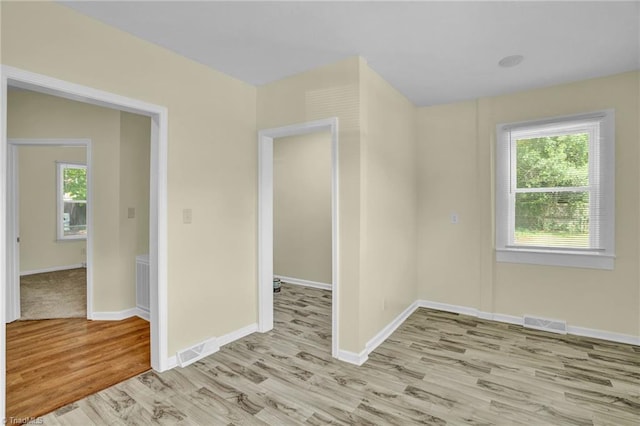 spare room with wood finished floors, visible vents, and baseboards