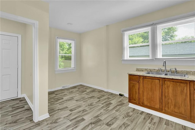 kitchen with light stone counters, sink, and light hardwood / wood-style floors