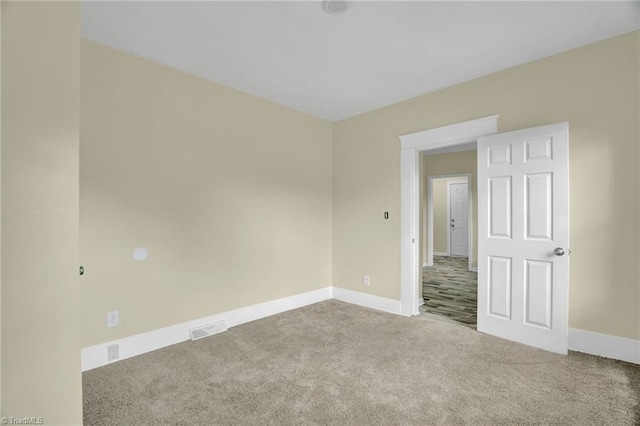 empty room featuring carpet, visible vents, and baseboards