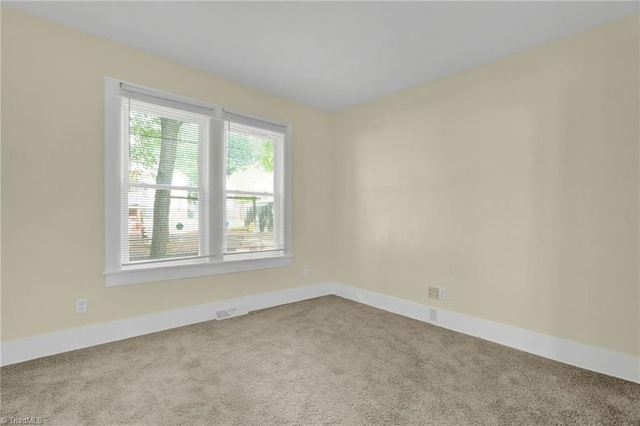 empty room featuring carpet flooring, visible vents, and baseboards