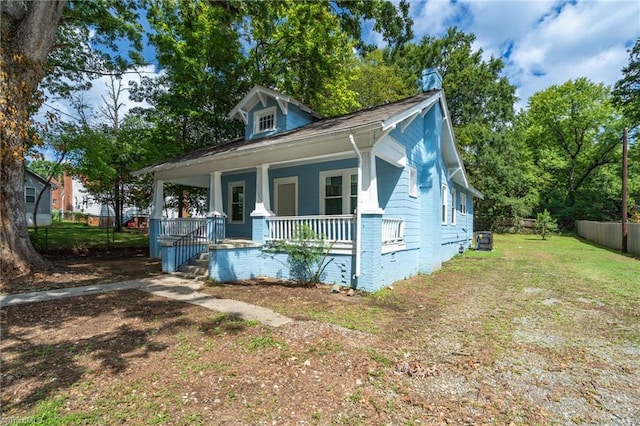 bungalow-style home with a front yard, covered porch, and central AC