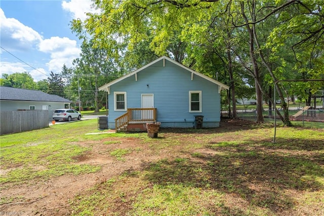 rear view of property featuring central air condition unit, a yard, and fence