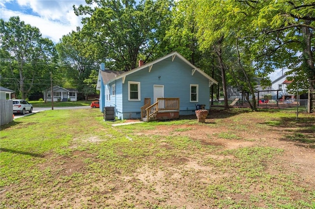 rear view of house featuring crawl space, cooling unit, a yard, and fence