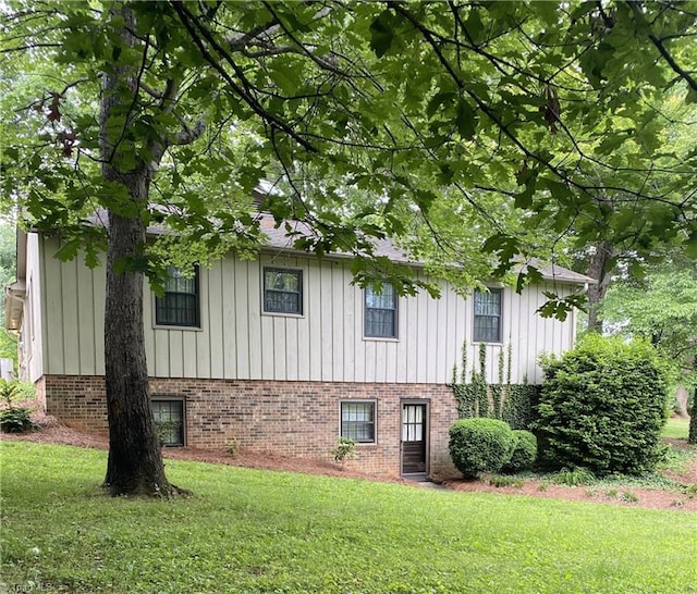 1229 Woodbrook Dr, Kernersville, NC 27284 - view of side of home with board and batten siding, a yard, and brick siding