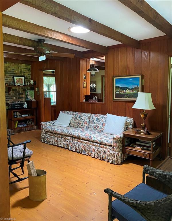 1229 Woodbrook Dr, Kernersville, NC 27284 - living room featuring beamed ceiling, wood finished floors, and wood walls