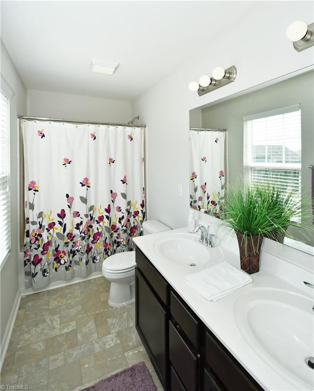 full bathroom featuring toilet, shower / tub combo, vanity, and a healthy amount of sunlight