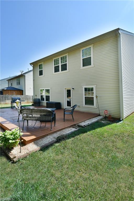 back of house featuring a deck and a lawn