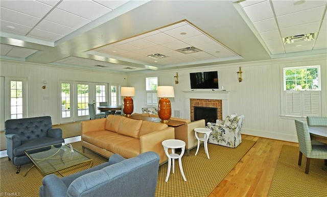 living room featuring a paneled ceiling, light hardwood / wood-style flooring, and a brick fireplace