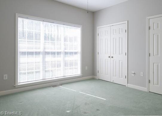 unfurnished bedroom with carpet floors, multiple windows, and baseboards