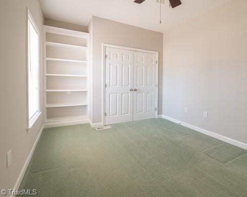 unfurnished bedroom featuring a closet, baseboards, carpet flooring, and multiple windows