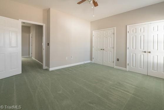 unfurnished bedroom featuring carpet floors, a ceiling fan, baseboards, and multiple closets