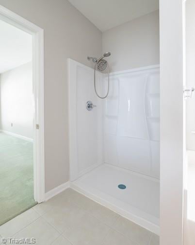 full bathroom with a shower, tile patterned flooring, and baseboards