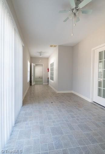 spare room with a ceiling fan and baseboards