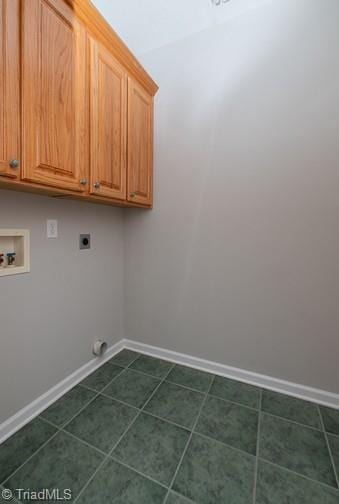 clothes washing area with hookup for a washing machine, cabinet space, hookup for an electric dryer, dark tile patterned floors, and baseboards