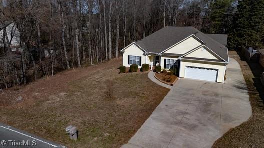 single story home with a garage, driveway, and a view of trees