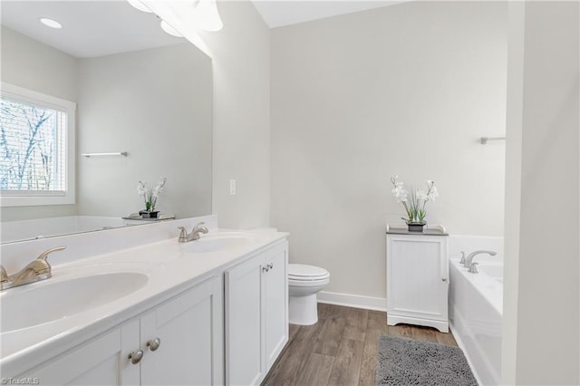 full bathroom with a sink, toilet, wood finished floors, and a bath