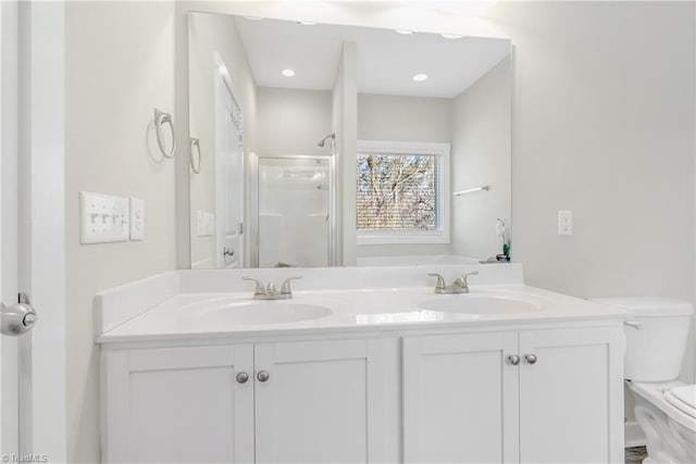 bathroom featuring double vanity, a shower stall, toilet, and a sink