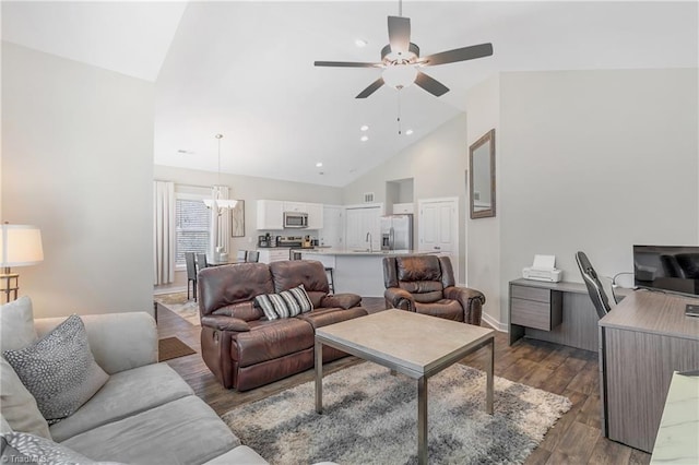 living area featuring wood finished floors, baseboards, high vaulted ceiling, recessed lighting, and ceiling fan with notable chandelier