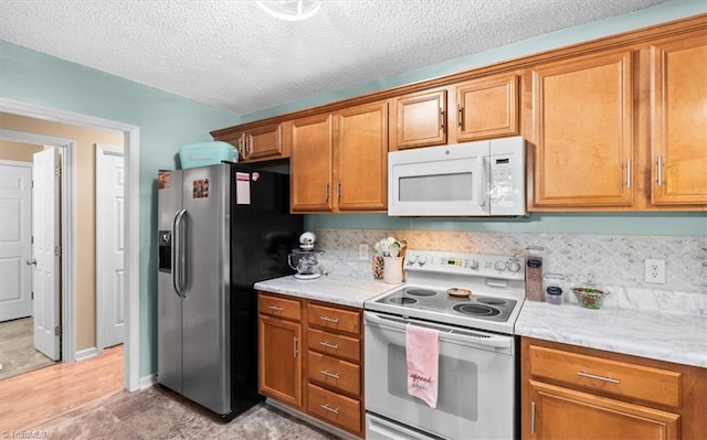 kitchen featuring a textured ceiling, light stone counters, and white appliances