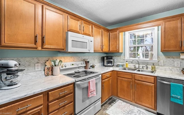 kitchen featuring electric range, dishwasher, sink, light stone counters, and a textured ceiling