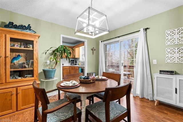 dining area with a textured ceiling, hardwood / wood-style flooring, an inviting chandelier, and sink