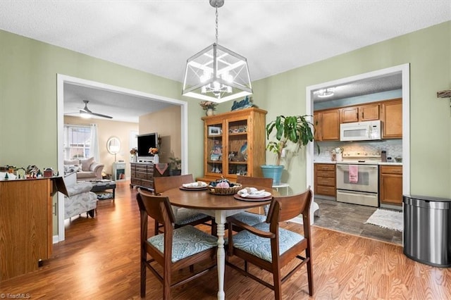 dining room featuring a textured ceiling, wood-type flooring, and ceiling fan with notable chandelier