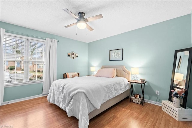 bedroom featuring a textured ceiling, light wood-type flooring, and ceiling fan