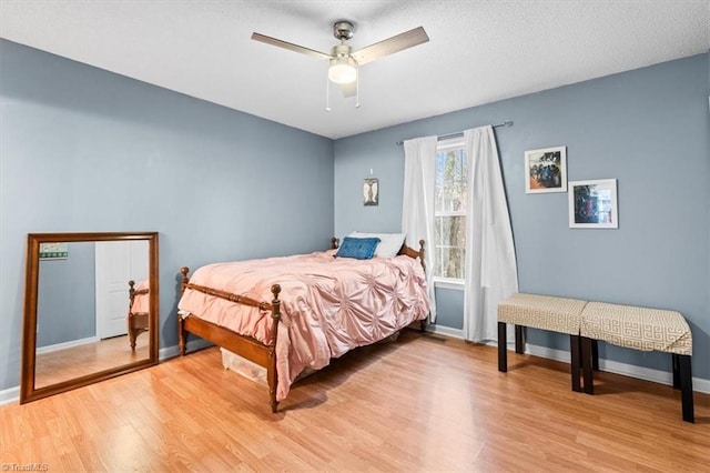 bedroom with ceiling fan, light hardwood / wood-style floors, and a textured ceiling