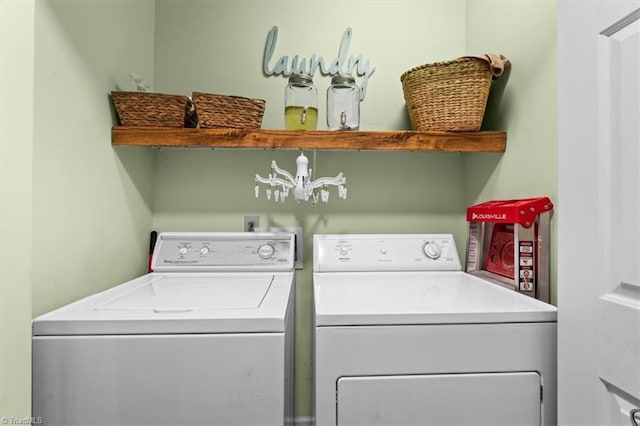 clothes washing area featuring washer and dryer and an inviting chandelier