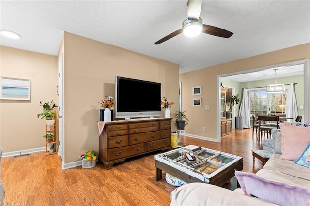 living room with ceiling fan, a textured ceiling, and light hardwood / wood-style flooring